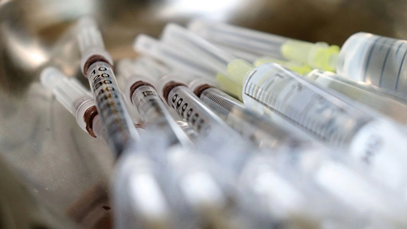 En metallskål fylld med vaccinationssprutor.