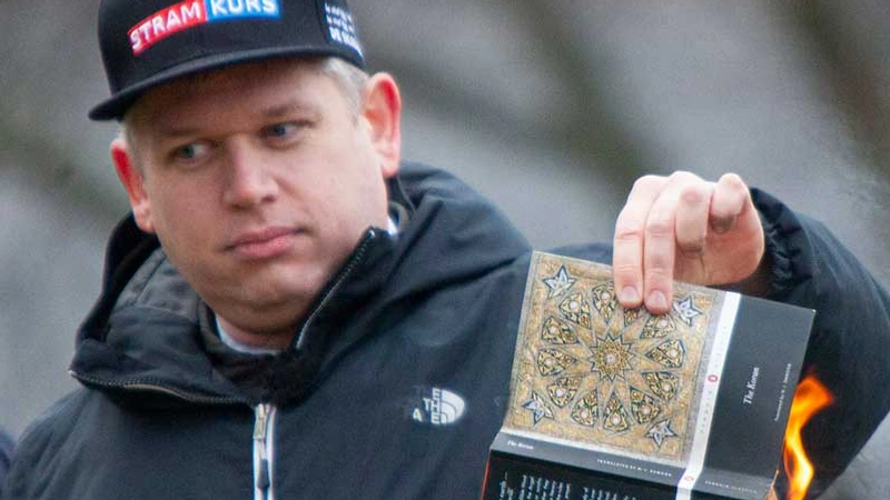 Rasmus Paludan som håller in brinnande Koran i sin hand.