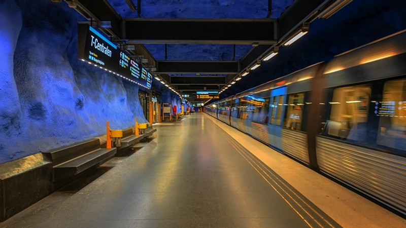 Ett tunnelbanetåg som passerar en station bredvid en perrong.
