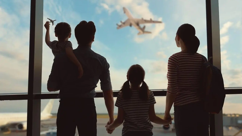 En familj som tittar ut genom ett fönster på en flygplats.
