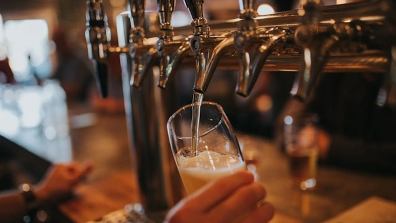 En person som häller upp ett glas öl på en bar.