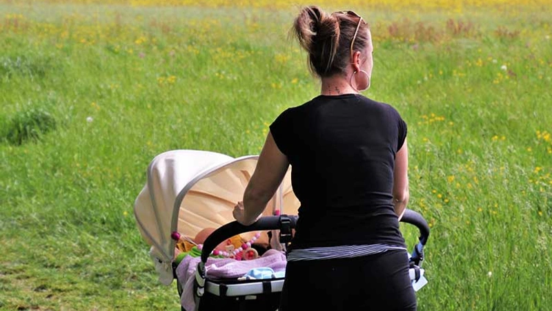 En kvinna som skjuter en barnvagn med en baby i.